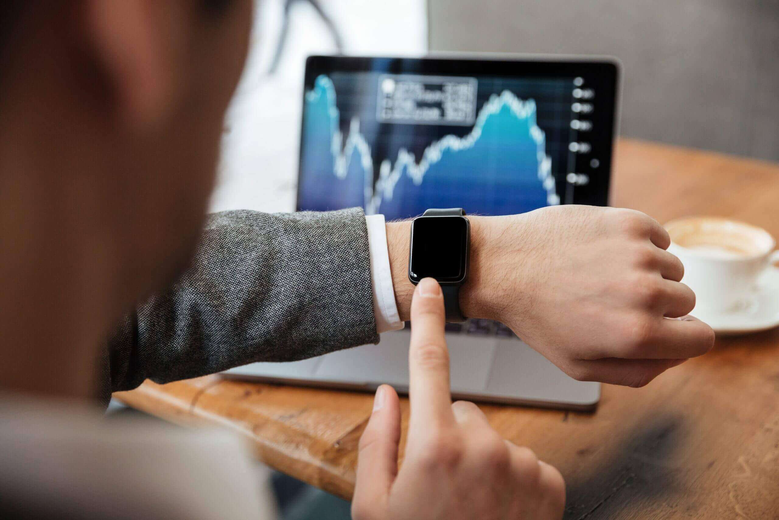 cropped image businessman sitting by table cafe analyzing indicators laptop computer while using wristwatch scaled 1